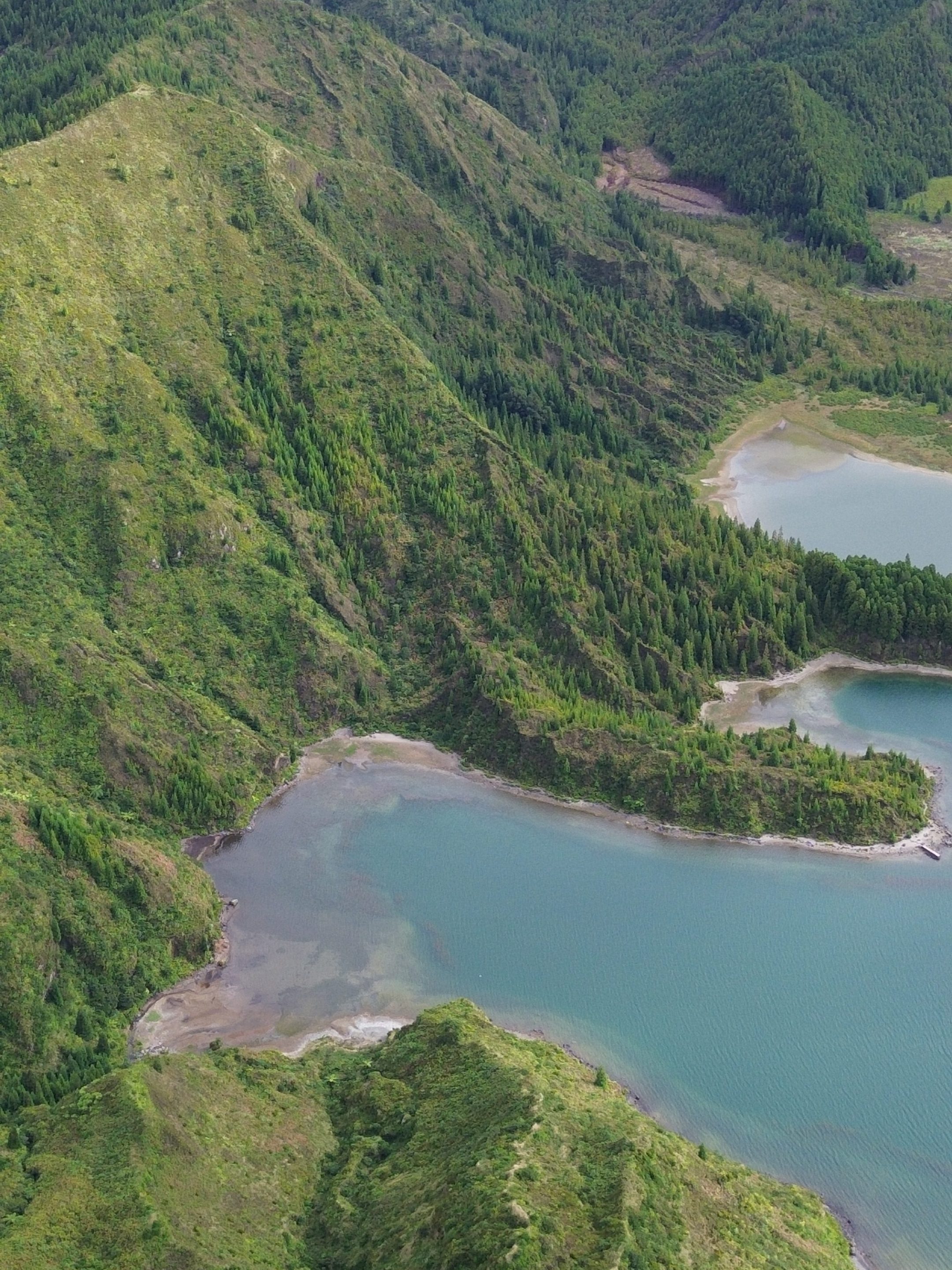 Aerial view of green hills and a blue lake in a mountainous landscape.